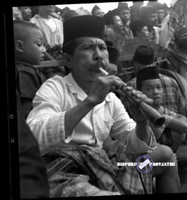 Seorang lelaki sedang meniup terompet  mengiringi tarian tradisional, foto diambil  pada saat keg...