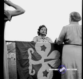 Seorang pandu sedang menyerahkan bendera kepada pembina pandu pada peringatan hari Boden Powell d...